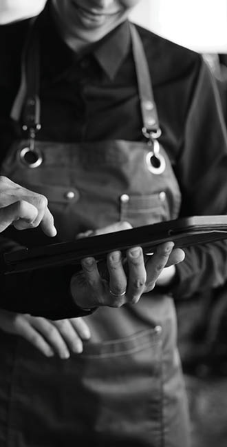 Two people wearing aprons are looking at a tablet computer. AI generated content