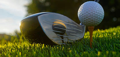 Golf clubs and balls on a green lawn in a beautiful golf course with morning sunshine. Close up of golf equipment on green grass.                                