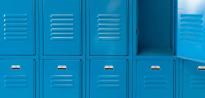 Single open empty blue metal locker along a nondescript hallway in a typical US High School. No identifiable information included and nobody in the hall.   