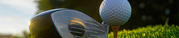 Golf clubs and balls on a green lawn in a beautiful golf course with morning sunshine. Close up of golf equipment on green grass.                                