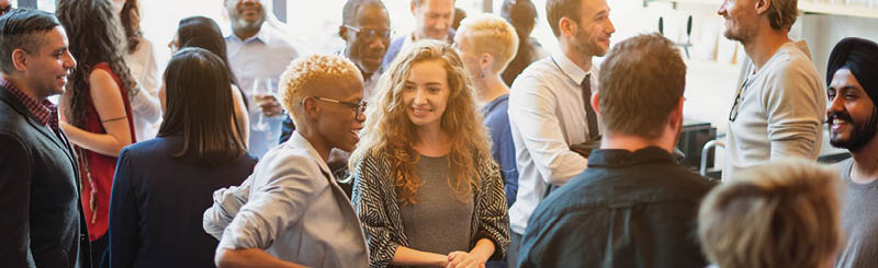 Diverse group of people socializing at a casual gathering. Men and women of various ethnicities engaged in conversation, enjoying a lively social event. Diverse people mingle at a social event.