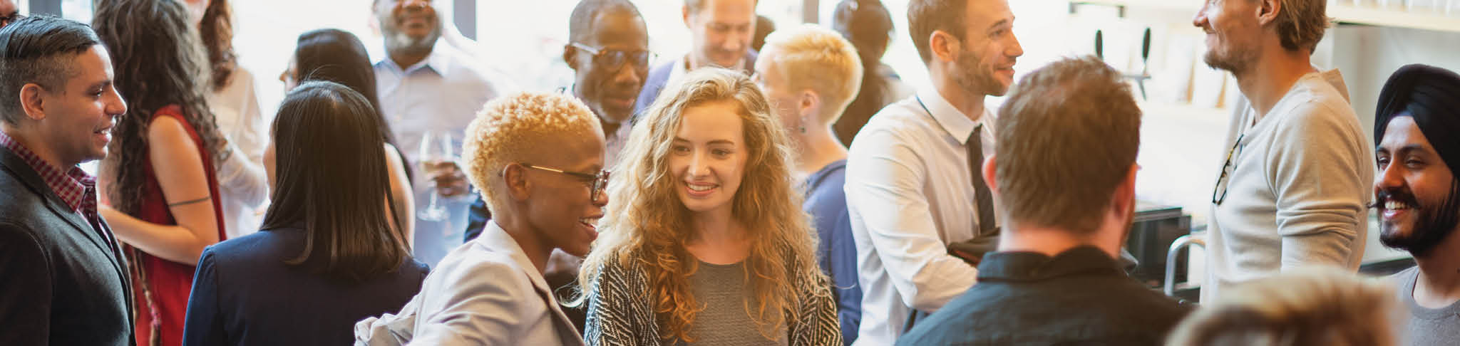 Diverse group of people socializing at a casual gathering. Men and women of various ethnicities engaged in conversation, enjoying a lively social event. Diverse people mingle at a social event.